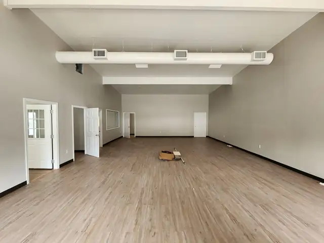 Open commercial room with new wood-look flooring and white walls